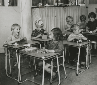 876936 Afbeelding van een groepje kinderen aan tafeltjes op de RK Kleuterschool (Waterstraat 4) in Wijk C te ...